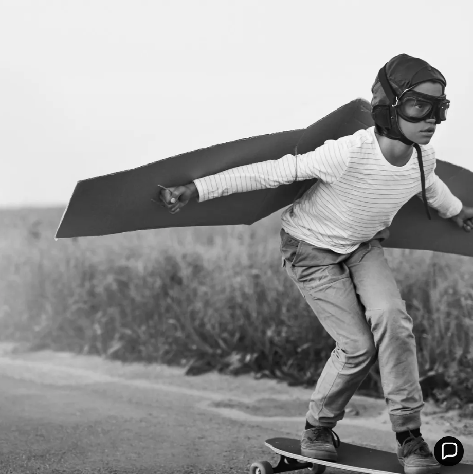Child with cardboard wings on a skateboard — dream big